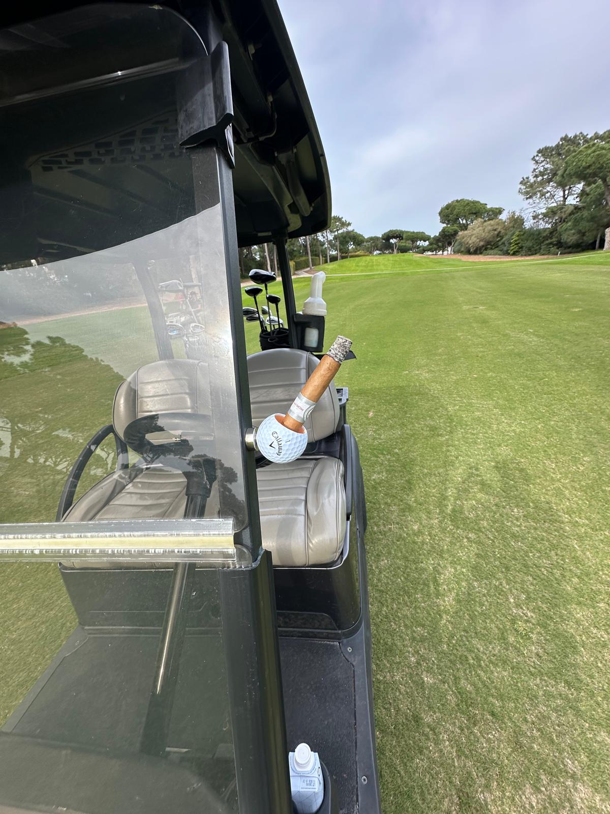 Golfball Zigarrenhalter Set auf einem Golfcart auf dem Platz, ideal für Golfer und Zigarrenliebhaber.